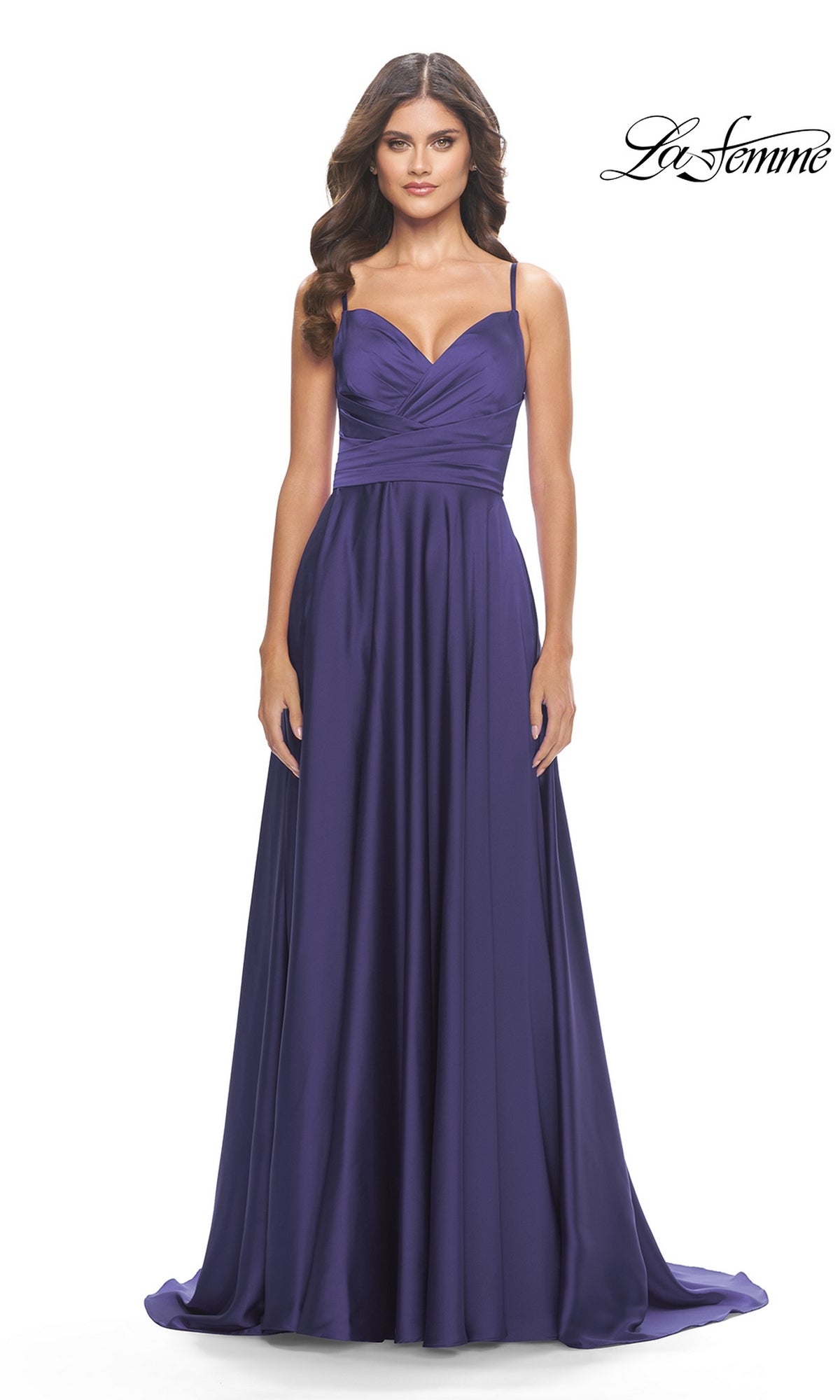 A woman stands against a white background wearing the La Femme Open-Back A-Line Designer Prom Dress 31233, featuring a floor-length deep purple skirt, thin straps, and a fitted ruched bodice.